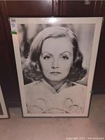Framed black and white Greta Garbo poster showing her face with a medium hairstyle, in a 32x44 inch black frame with white matting.
