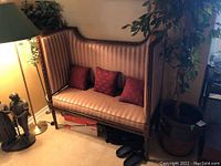 Full view of vintage striped high back settee with wood frame and three red cushions