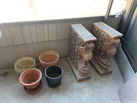 Overall view showing two terra cotta blocks and four round pots arranged on balcony floor