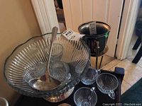 Glass punch bowl with ribbed glass design, seated on silver plate base, along with 6 glass cups inside and a silver ladle.