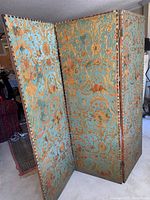 Folding screen front view showing turquoise side with embossed gold floral and scroll pattern