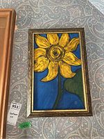 Full view of sunflower painting on board with gold frame, mounted on patterned wallpaper background.