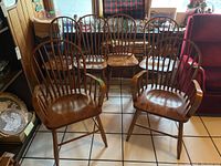 Group view of six wooden chairs; two captain's chairs with armrests at front and four side chairs at back, showcasing overall condition and design.