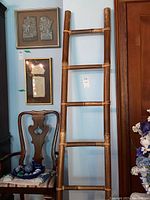 Full view of the bamboo ladder leaning against blue wall beside wooden door and chair