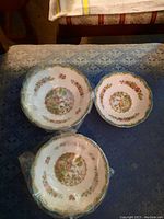 Three bowls with detailed bird and floral design, gold rim detail, and intricate border.