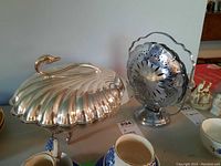 Silver-tone sectional shell-shaped serving dish with lid and reflective polished finish.