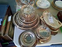 Photo showing assorted silver-plated trays, bowls, and a two-tiered serving tray with ornate decorative designs and cutouts.