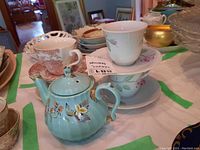 Porcelain teapot with floral design and Rose Bloom and Mason's tea cups and saucers on table