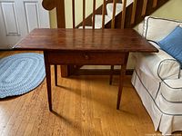 Front and side view of the antique wooden tavern table showing breadboard top, central drawer, and tapered legs.