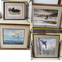 Four framed prints arranged on a couch showing ducks, a hunter and dog, flying ducks, and a bird on a tree.