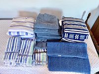Top-down view of the towels and bath mats folded and stacked on a bed showing various sizes and patterns.