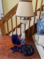 Table setup with antique white swirl glass lamp, three cobalt blue glass vases, star-shaped tealight holder, dragonfly thermometer, and two string-wrapped glass ornaments