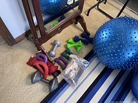 Photo of various dumbbells, resistance bands, and an exercise ball near a mirror.