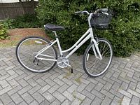 Photo showing the full Raleigh Detour 4.5 white bicycle with black front basket, black saddle, and tires on paved surface.