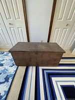Front view of antique wooden chest showing rectangular shape and worn wood.