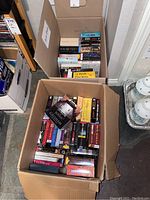 Two cardboard boxes filled with assorted CD audio books.