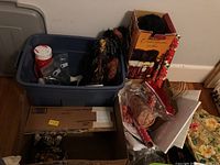 Wide view of plastic bins and boxes with Christmas decorations and wrapping paper set on floor