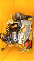 Photo showing Craftsman drill, sander, staple gun, cords and assorted hand tools including screwdriver and pliers arranged in a yellow bin.