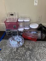 Overall view of multiple plastic storage containers and organizers with and without lids in clear and colored plastic.