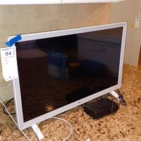 Front and angled views of the LG 24-inch Smart TV with white bezel and power adapter on countertop.