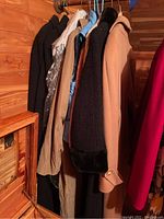 Side view showing various coats and sweaters hung on a rod including camel, black, blue, and beige items.