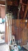 Photo showing wooden tiki torch poles with bamboo torch heads and black metal decorative torch holders and stands clustered together.