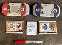 Two metal collectible cases for 2001 NHL All-Stars featuring Jean Beliveau and Denis Potvin, with two hockey cards and a Sharpie marker for scale.