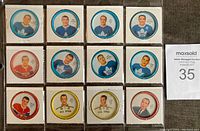 Front view of 12 Shirriff hockey coins with colored borders and player portraits including Gordie Howe, Frank Mahovlich, Dave Keon, Doug Harvey.