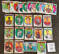 Front side of 28 1971-72 O-Pee-Chee hockey cards laid out in three rows, showing various players including Bobby Orr, Phil Esposito, Henri Richard, Jean Ratelle among others. Cards have colorful team names and player portraits, all with original gloss and some wear.