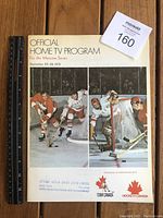Front cover of the official Home TV program showing hockey players in action, date and event details, Ford and hockey team logos. A ruler beside it shows scale.