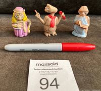 Three 1982 E.T. figurines by LJN Toys, shown next to a pen for scale, approximately 2 1/4 inches tall each.