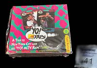 Front view of sealed colorful wax box featuring several hip-hop artists and text promoting a trip contest.