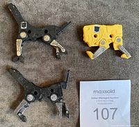 Three small plastic dog-like dinosaur Transformers figures, two black and one yellow with silver legs, displayed on fabric background.