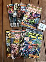 Lot of 8 Marvel Master of Kung Fu comic books laid out on wooden surface, showing various colorful action covers from 1975-1980 depicting Shang-Chi and other characters.