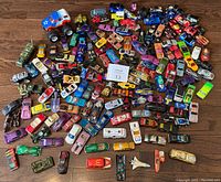 Top view of approximately 170 diecast vehicles spread out on a floor including cars, trucks, boats and a space shuttle.