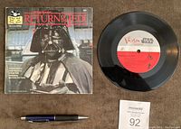 Photo showing the vinyl record with red and white Vista Star Wars label next to the read along book cover featuring Darth Vader image.