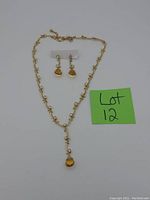 Photo of vintage costume jewelry necklace and earrings set with amber-colored stones on a white background with lot label next to it.