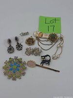 Full view of all vintage costume jewelry including earrings, brooches, hairpin, and clips arranged on a white surface