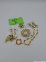 Photo showing vintage costume jewelry lot with various brooches, earrings, and bracelet necklace set.