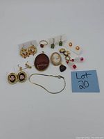 Overview of all vintage costume jewelry items in lot including earrings, pendants, bracelet, and ring with lot number 20 card