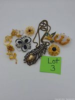 Image showing assortment of vintage and modern costume jewelry with various brooches, a necklace, and earrings laid out on a white background with a green Lot 3 card.