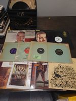 Full view of vinyl collection showing several 78 rpm records in sleeves, LP albums with artistic covers, and a crate for storing vinyls.