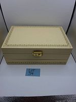 Closed view of the cream vintage jewelry box with gold floral trim and a clasp
