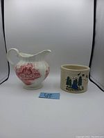Photo showing the Johnson Bros milk jug with red scenic transfer design and the Roseville Pottery planter with painted nature-themed design side by side on a white background.