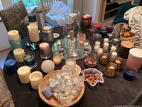 Wide view of assorted candles including large pillar candles, votives, tea lights, dried potpourri, and old mirror tray on table
