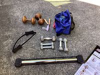 Photo of the exercise equipment including dumbbells, bowling ball, jump rope, resistance bar, carrying bag, and exercise chart.