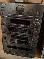 Stacked Pioneer stereo components comprising amplifier, tuner, cassette deck, and CD player in black finish with various controls and displays.