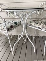 Side view of the metal patio table and chairs showing the floral cushions and distressed white paint