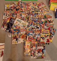 Photo showing an overhead arrangement of 57 assorted Archie comic books including single issues and double digests, featuring characters like Archie, Jughead, Betty and Veronica in full color covers.