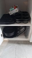 Photo of shelving unit with six Nordicware muffin pans, springform pan, wire racks, and oven glove.